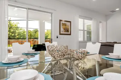 a dining room with a glass table and white chairs at Vacation Paradise Home, Private Pool, Game Room BL102 in Kissimmee