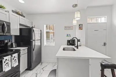 a kitchen with a sink and a black refrigerator at The Villas at Seven Dwarfs - 4564 Luxury Villa - Near Disney - Water Park in Kissimmee