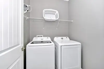 a small white laundry room with a washer and dryer at Astounding Home Near Disney With Themed & Media Room, Pool Table With Waterpark & Resort Access At Encore Resorts Reunion - 240Cl in Kissimmee