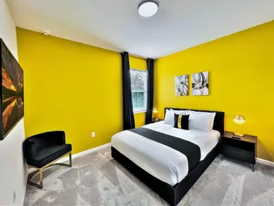 a yellow bedroom with a bed and a chair at BV310MB - Disney & Universal heroes - 16 guests in Kissimmee