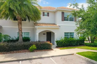 a white house with a palm tree and a driveway at Storey Lake Dreamy Townhome, 5 mi Disney Universal in Kissimmee