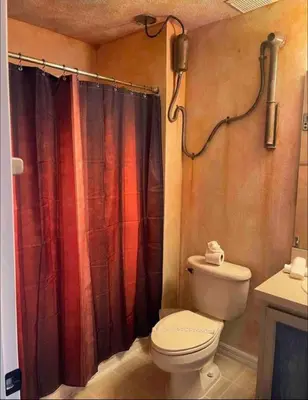a bathroom with a toilet and a red shower curtain at Enchanted Jungle Themed Home Pool 3mi to Disney in Kissimmee