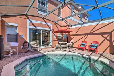 a house with a swimming pool with chairs and an umbrella at Enchanted Jungle Themed Home Pool 3mi to Disney in Kissimmee