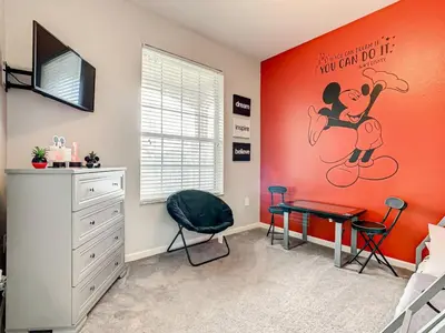 a bedroom with an orange wall with a bed and a desk at Windsor Hills Mickey Mouse Condo, 2.5mi Disney in Orlando
