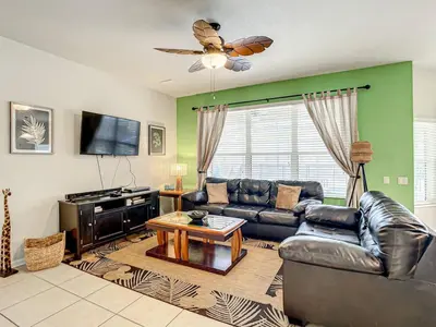 a living room with a leather couch and a tv at Windsor Hills Themed Home Pool Spa 2.5mi Disney in Orlando