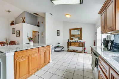 a kitchen with wooden cabinets and a tile floor at 4 Mi to Disney Spacious Retreat with Pool and Yard! in Kissimmee