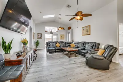 a living room with leather furniture and a ceiling fan at 4 Mi to Disney Spacious Retreat with Pool and Yard! in Kissimmee