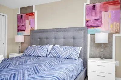 a bedroom with a bed with two lamps and paintings at Comfy House at Compass Bay CB102 in Kissimmee