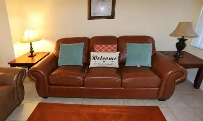 a brown leather couch sitting in a living room at UniDisL 3Br3B near Disney quiet resort community, pool, private hot tub, BBQ & games in Kissimmee
