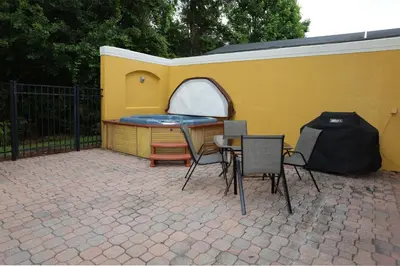 a patio with a table and chairs next to a yellow wall at UniDisL 3Br3B near Disney quiet resort community, pool, private hot tub, BBQ & games in Kissimmee