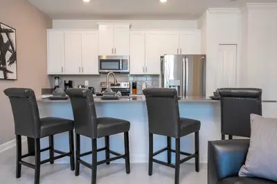 a kitchen with white cabinets and a counter with chairs at 4Bd Close to Disney with Pool at Storey Lake 2560 in Kissimmee