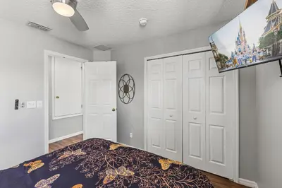 a bedroom with a bed and a flat screen tv at 7BDM Prvt Pool Villa - Gated Resort 10min to Disney in Kissimmee