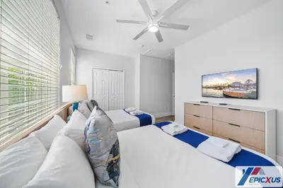 a white bedroom with a couch and a tv at The Epic Toronto Vista Cay Orlando in Orlando