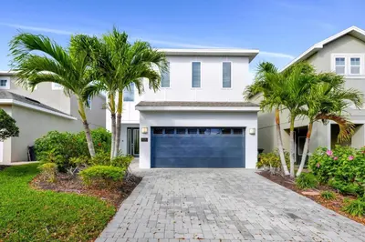a white house with palm trees and a garage at Elegant Home Near Disney With Game & Themed Rooms With Waterpark & Resort Access At Encore Resorts Reunion - 400La in Kissimmee