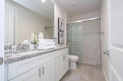 a white bathroom with a toilet and a glass shower at Amazing 2024 Villa 5 min to Disney in Orlando