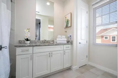 a white bathroom with a sink and a mirror at Amazing 2024 Villa 5 min to Disney in Orlando