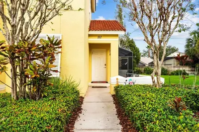 a yellow house with a white door and trees at 4 Bedroom 3 Bathroom Terra Verde 111PB in Kissimmee