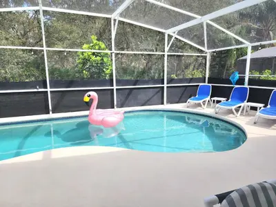 a pink flamingo in a swimming pool with two chairs at Home Close to Disney Parks/Amazing Private Pool in Orlando