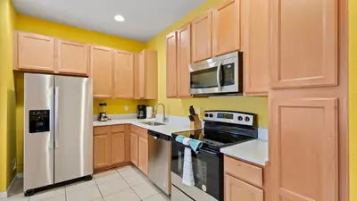 a kitchen with wooden cabinets and stainless steel appliances at Shvck3 - Coral Cay Resort #3 - 4 Bed 3 Baths Townhome in Kissimmee