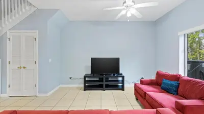 a living room with a red couch and a flat screen tv at Shvck4 - Coral Cay Resort #4 - 4 Bed 3 Baths Townhome in Kissimmee