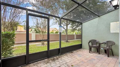 a patio with two chairs and a table with windows at Shvck5 - Coral Cay Resort #5 - 4 Bed 3 Baths Townhome in Kissimmee