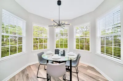 a dining room with a table and chairs and windows at Near Disney - 3BR Condo - Games Pool & Sauna in Orlando