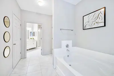 a white bathroom with a tub and a sink at Near Disney - 3BR Condo - Games Pool & Sauna in Orlando