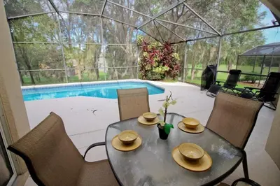 a dining table and chairs with a view of a pool at Gorgeous 4 Bed Home In Gated Community! villa in Kissimmee