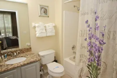 a bathroom with a toilet and a shower curtain with purple flowers at Gorgeous 4 Bed Home In Gated Community! villa in Kissimmee