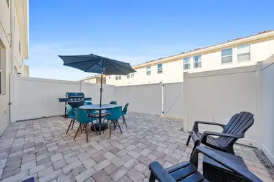 a patio with a table and chairs and an umbrella at Charming Challet at Compass Bay CB101 in Kissimmee