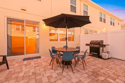 a patio with a table with an umbrella and a grill at Charming Challet at Compass Bay CB101 in Kissimmee