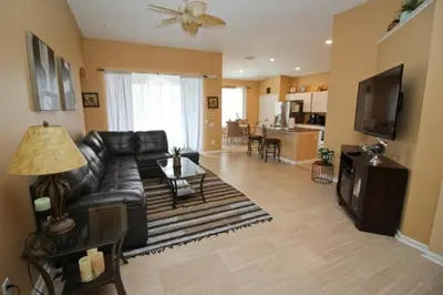 a living room with a black leather couch and a table at Luxury Villa With Private Pool And Great Game Room villa in Kissimmee