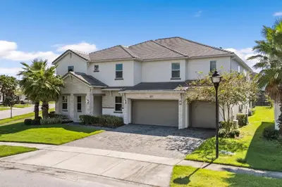 a white house with a garage and palm trees at UNIQUE MASTERPIECE15 Suites Sleeps 30 SON101 in Kissimmee