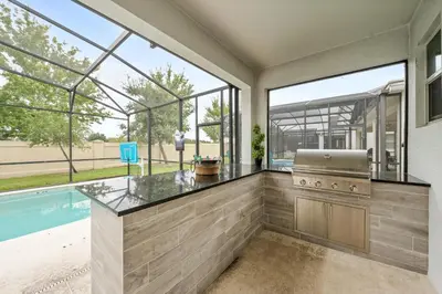 an outdoor kitchen with a swimming pool and windows at Luxury Villa w Pool, Home Cinema, BBQ & Near Disney Parks in Kissimmee