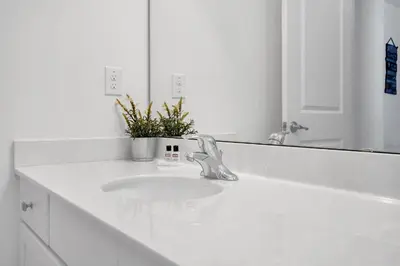 a white bathroom with a sink and a mirror at Luxury Villa w Pool, Home Cinema, BBQ & Near Disney Parks in Kissimmee