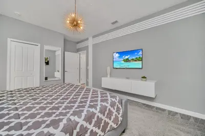 a white bedroom with a large bed and a painting on the wall at 9 BR Family Home 8 Minutes to Disney STL119 in Kissimmee