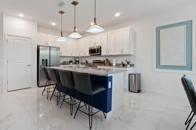 a kitchen with a large island with black bar stools at Stunning Modern Home VPR102 in Kissimmee