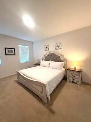 a bedroom with a bed and a night stand with a lamp at Lakeview Home Sleeps 25 VPR103 in Kissimmee