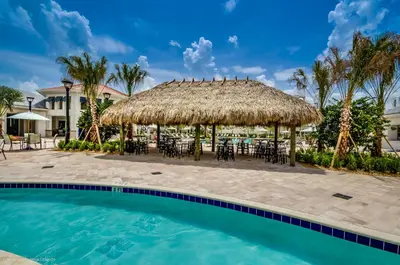 a resort with a large pool with chairs and a straw umbrella at 3141 Paradox Circle 406 in Kissimmee