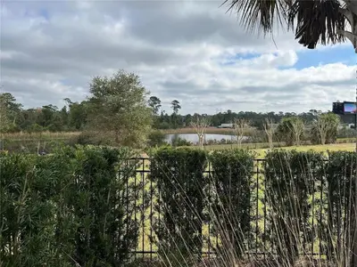 a fence in front of a field with a lake at 7491 Oasis at Reunion sleeps 12 in Orlando