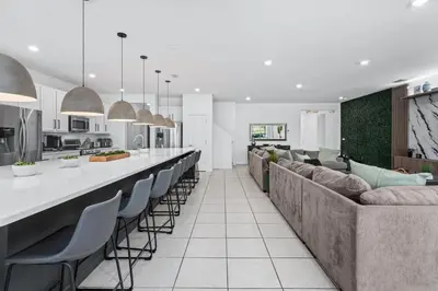 a kitchen and living room with a long bar with chairs at Unique Masterpiece 15 En-suites VPR104 in Kissimmee