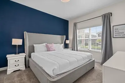 a bedroom with a large bed with a blue wall at Comfy Townhome 8 Min to Disney STL120 in Kissimmee