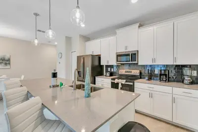 a kitchen with white cabinets and a table and chairs at Private Pool 8 Min to Disney STL121 in Kissimmee