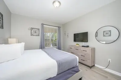 a white bedroom with a large bed and a mirror at Beautiful Lake View Condo, Vista Cay-1004 in Orlando