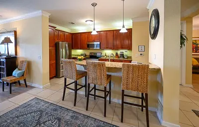 a kitchen with wooden cabinets and bar stools at Gorgeous 3 Bed Lakeview, Vista Cay - 1010 in Orlando