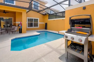 a swimming pool with a grill in front of a house at This Happy Place in Kissimmee