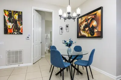 a dining room with a glass table and blue chairs at Premium Vista Cay Condo, Vista Cay - 2006 in Orlando