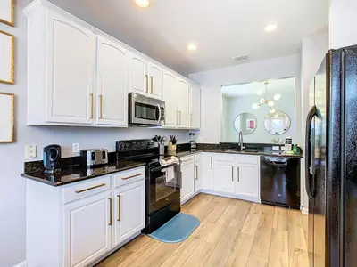a kitchen with white cabinets and black appliances at WH7820BS - 5 bedrooms - Pool - Theater - Resort in Orlando