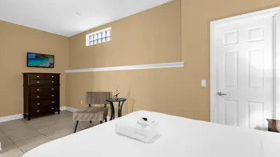 a bedroom with a white bed and a chair at Ultimate Summer Retreat - TownHome by Disney! in Orlando
