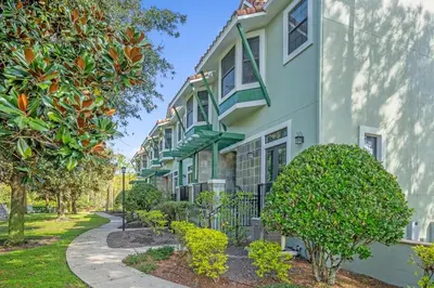 a building with green trim and trees next to a sidewalk at Sunny Summer in Orlando - TownHome by Disney! in Orlando
